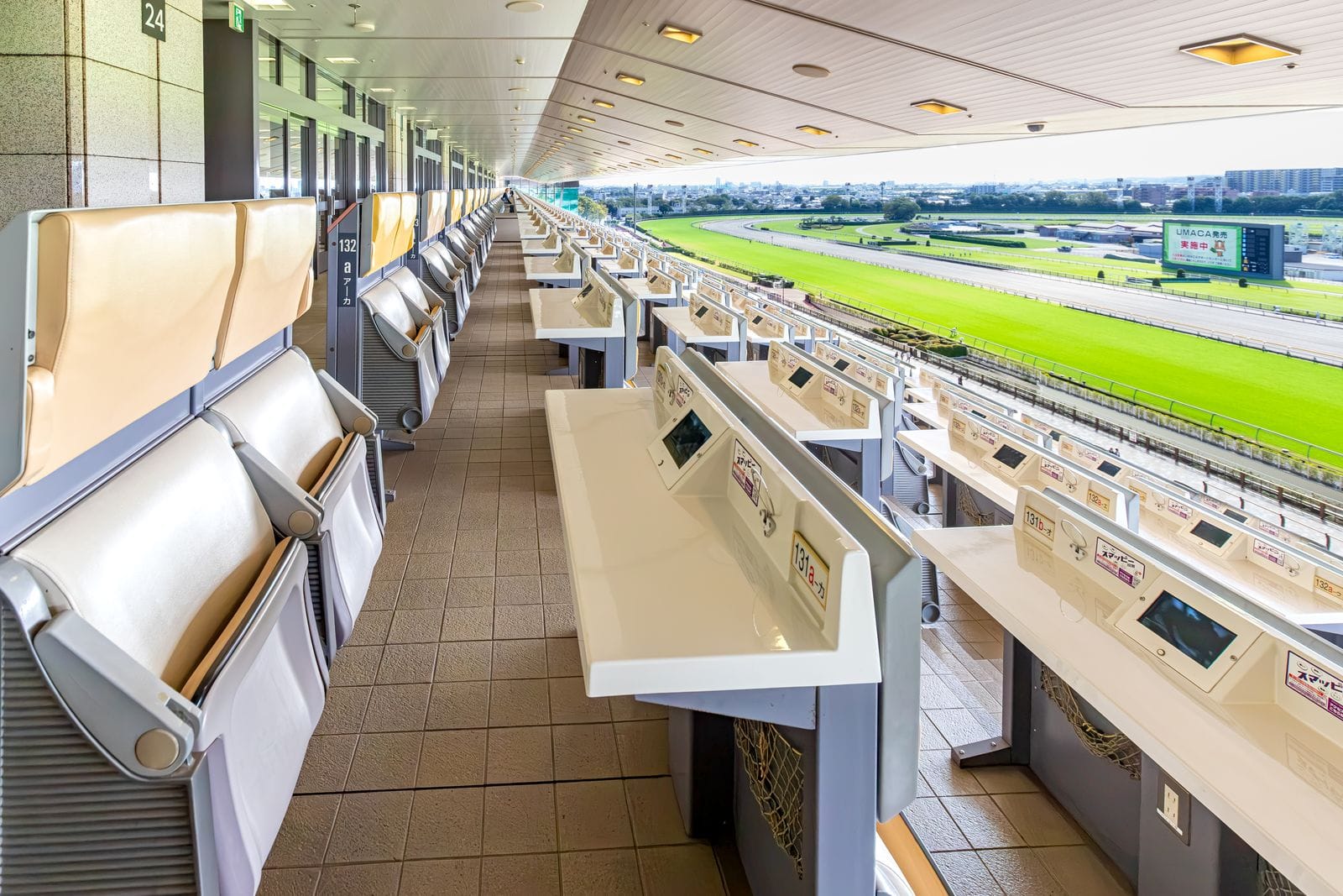 Rows of reserved seats with desks in the Fuji View Stand, overlooking the green turf course.