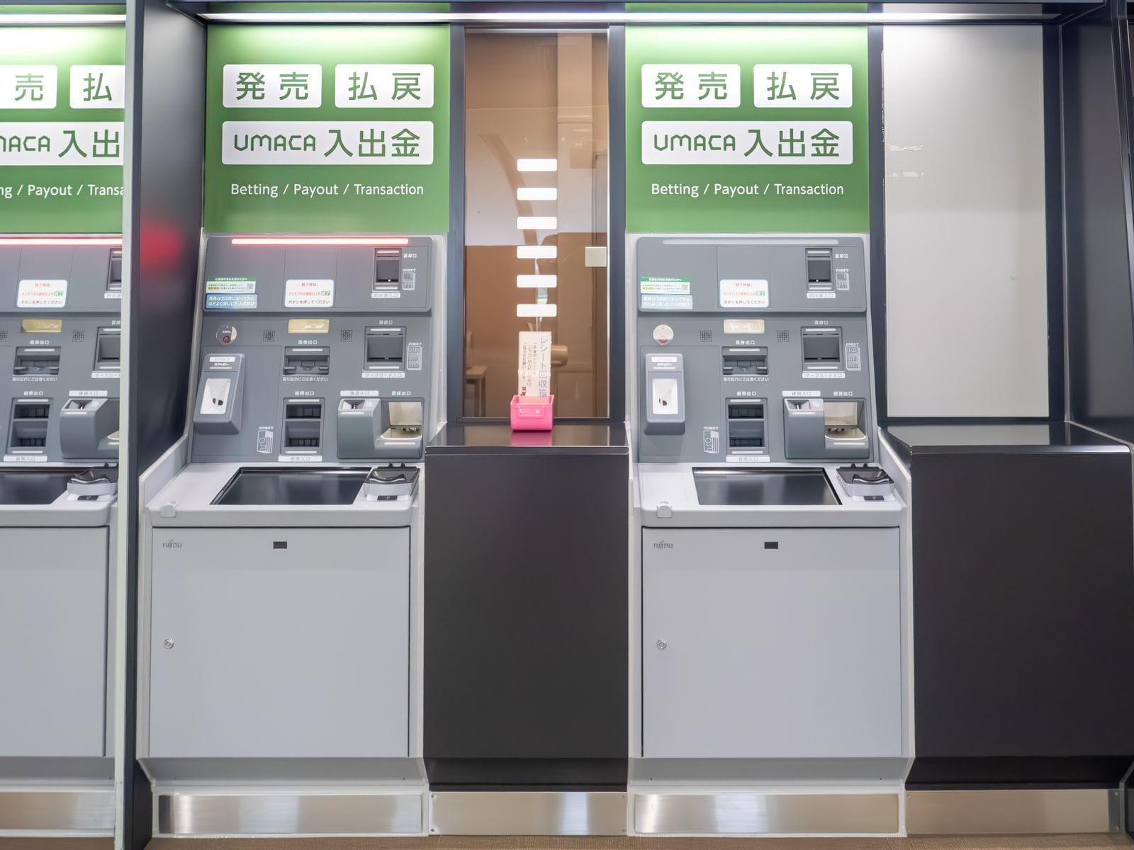 Two betting and payout machines at Tokyo Racecourse with signs reading Betting, Payout and Transaction.