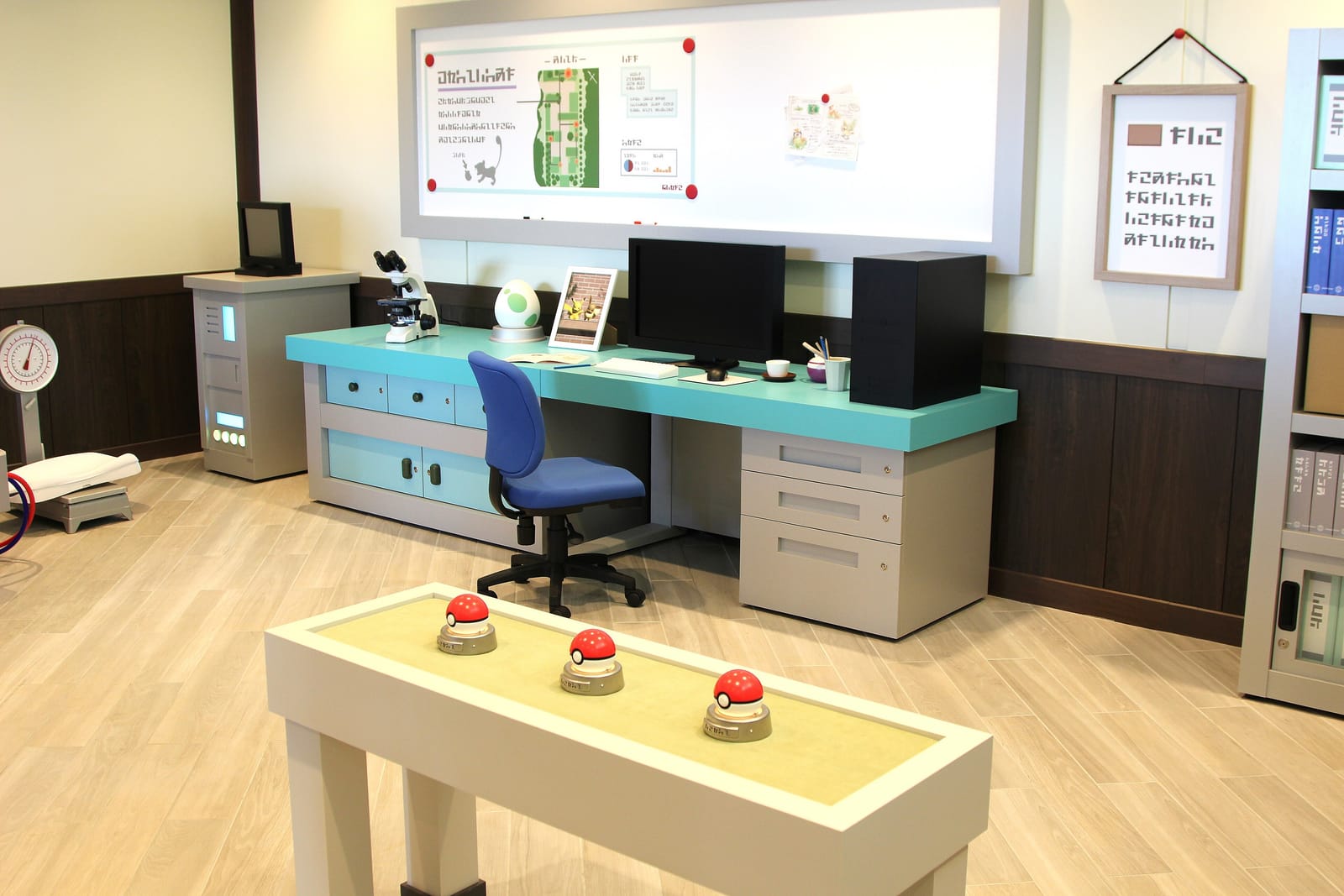 Inside the Pokémon Research Lab at PokéPark KANTO, a desk with computers and three Poké Balls on display.