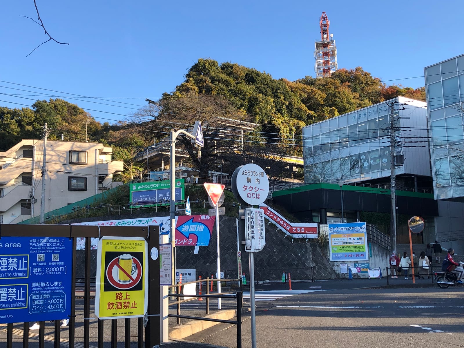 The street outside Keio-Yomiuri-Land Station, with stairs and signs leading up to the Sky Shuttle gondola station.