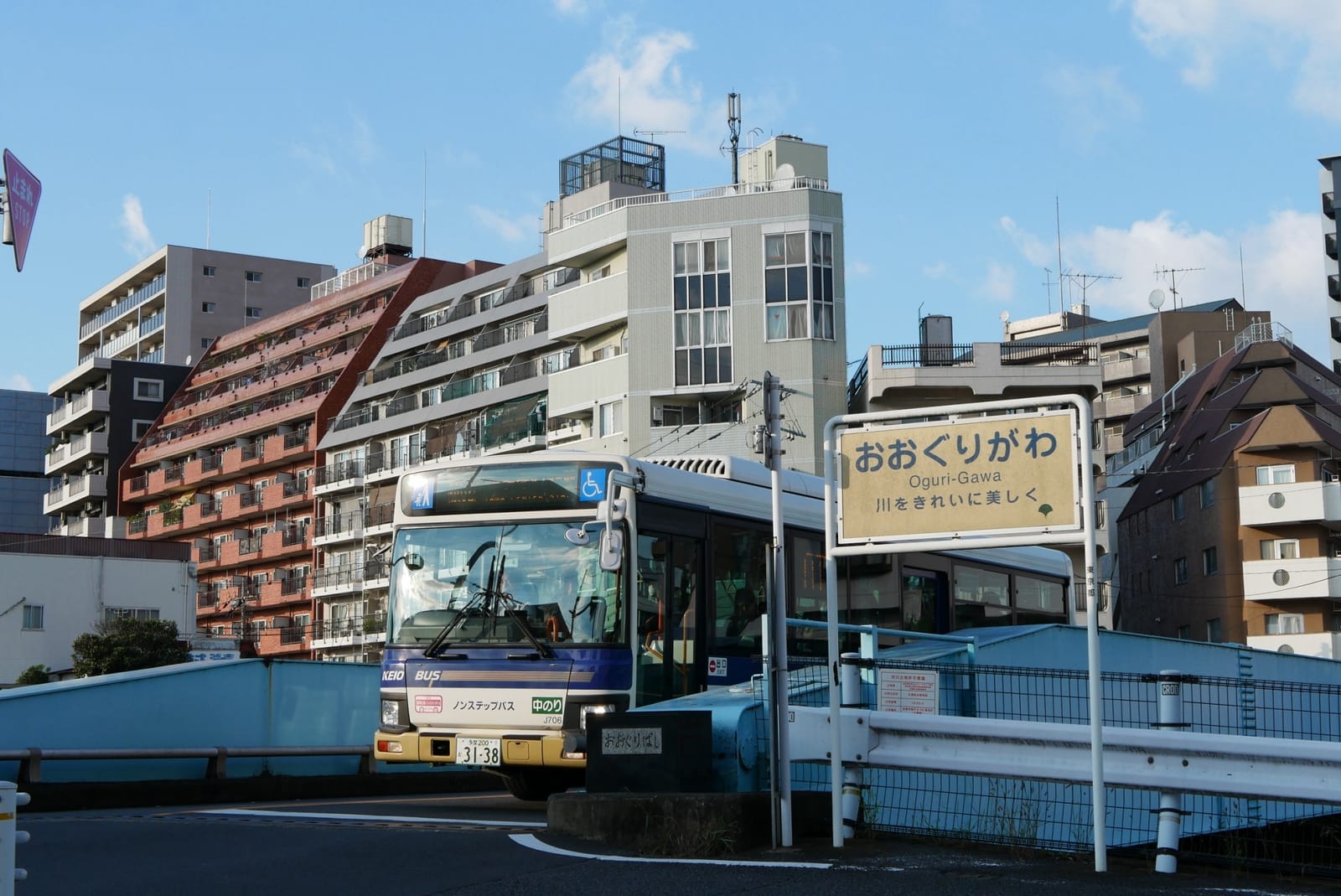 The river name sign for 大栗川 at the bridge, with a Keio bus crossing