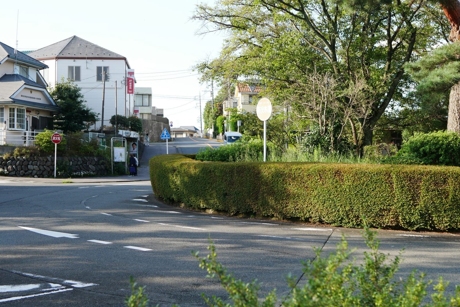 The Sakuragaoka roundabout, with its hedge-lined centre and houses on the hill